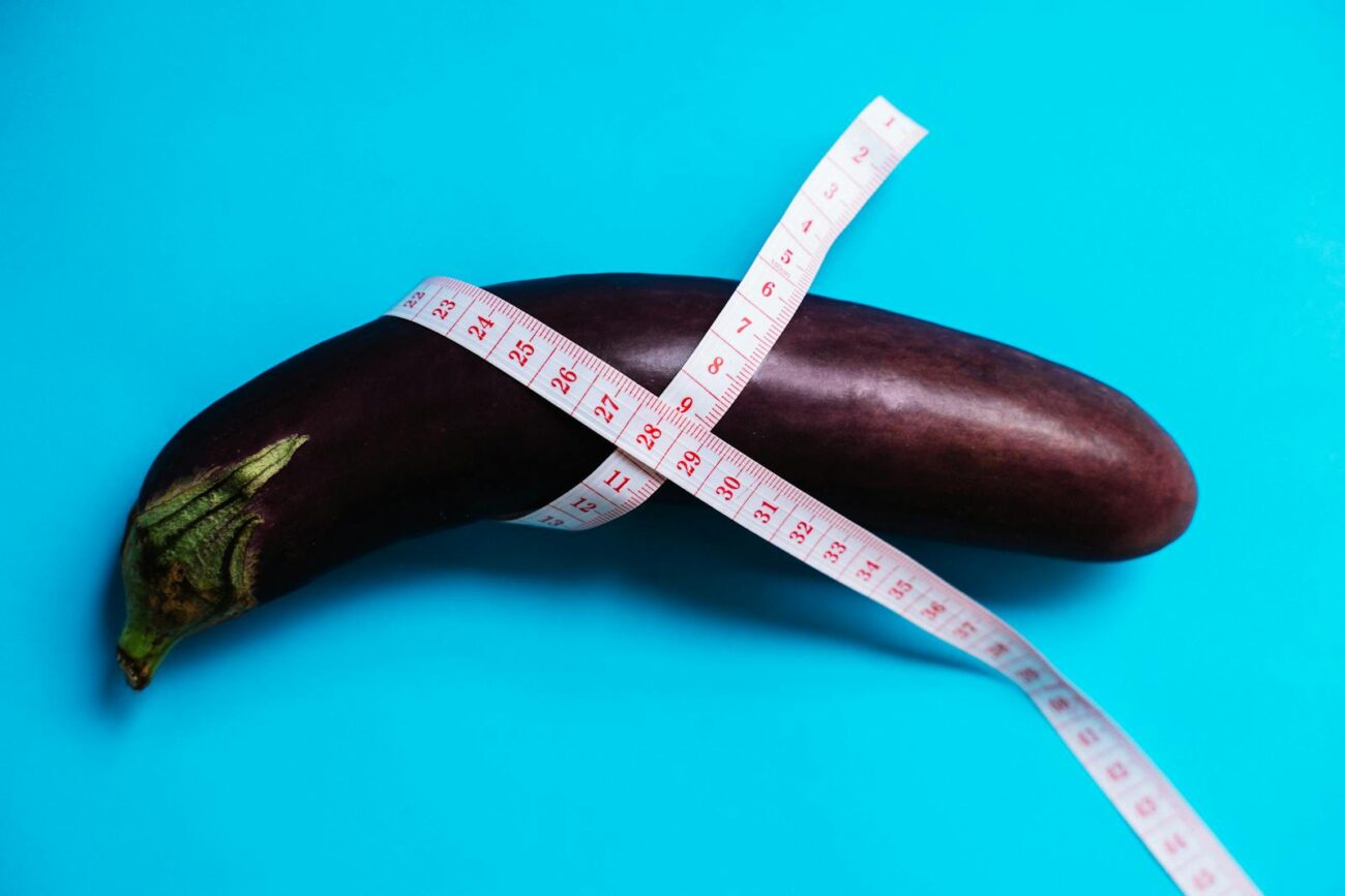 Close-up of an eggplant wrapped with a measuring tape on a vibrant blue background, concept of healthy eating.
