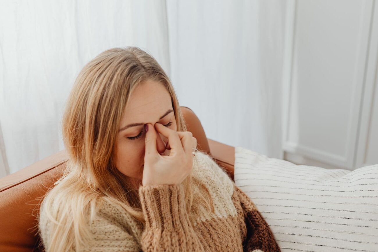A tired woman pinching the bridge of her nose, showing eye strain and fatigue